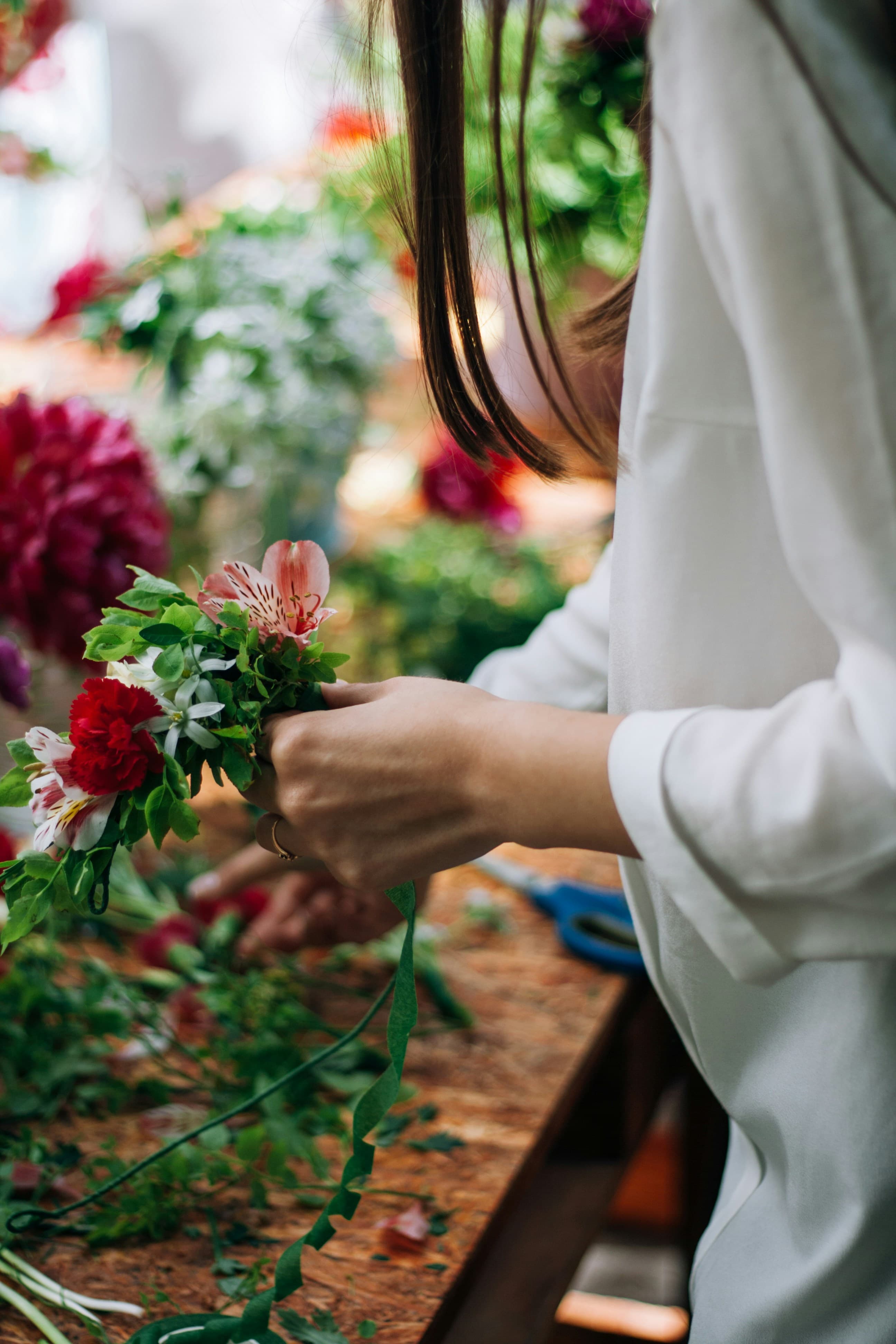 Florist arranging seasonal stems at a wooden workbench